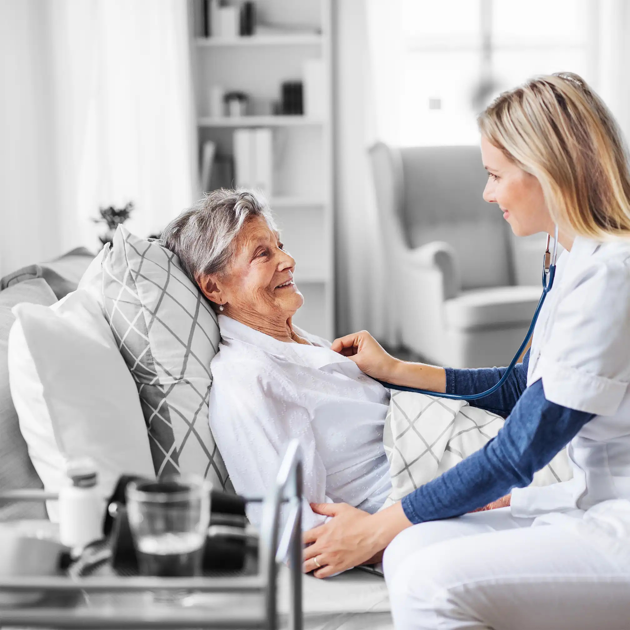 Nurse chatting to elderly lady in bed